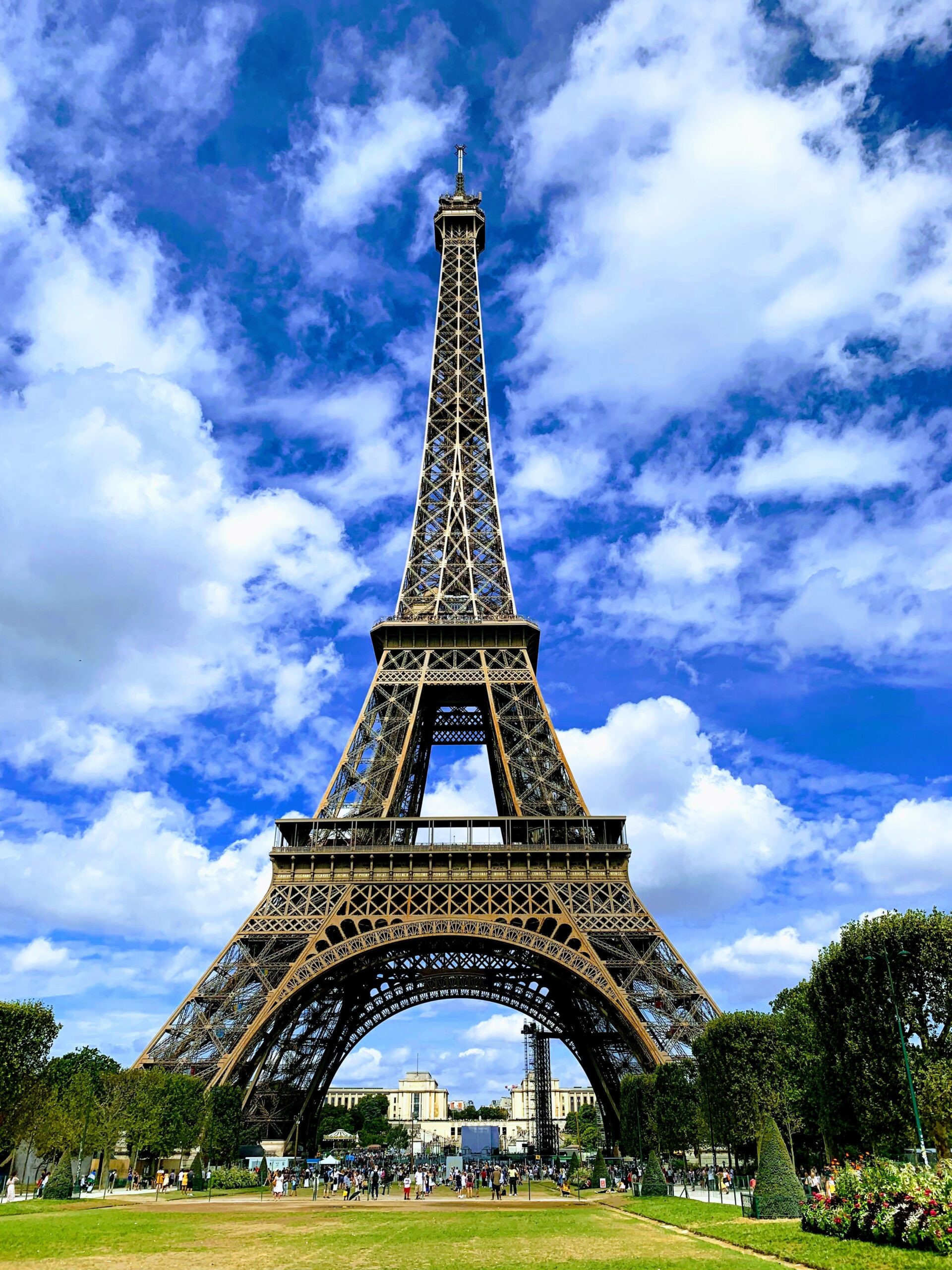 The iconic Eiffel Tower in Paris, France, against a blue cloudy background.